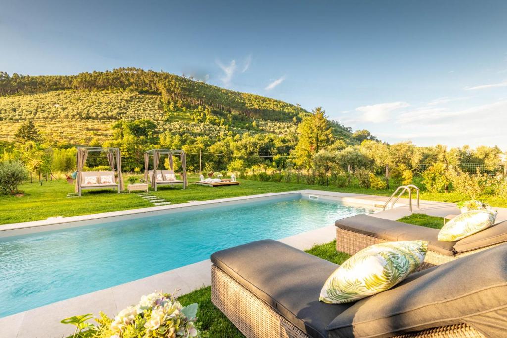 une piscine avec deux canapés devant une montagne dans l'établissement Villa Ester, a Stylish Farmhouse on the Hills, à Capannori