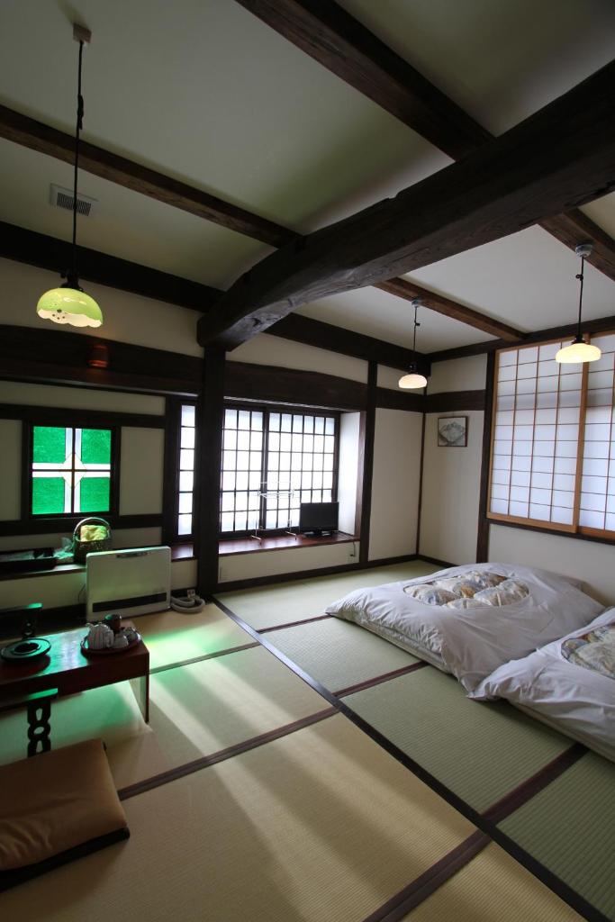 une chambre avec un lit, une table et des fenêtres dans l'établissement Minshuku Takizawa, à Takayama