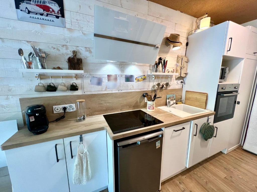 une cuisine avec des armoires blanches et un réfrigérateur blanc dans l'établissement Studio paisible au pied des pistes, à Villard-de-Lans