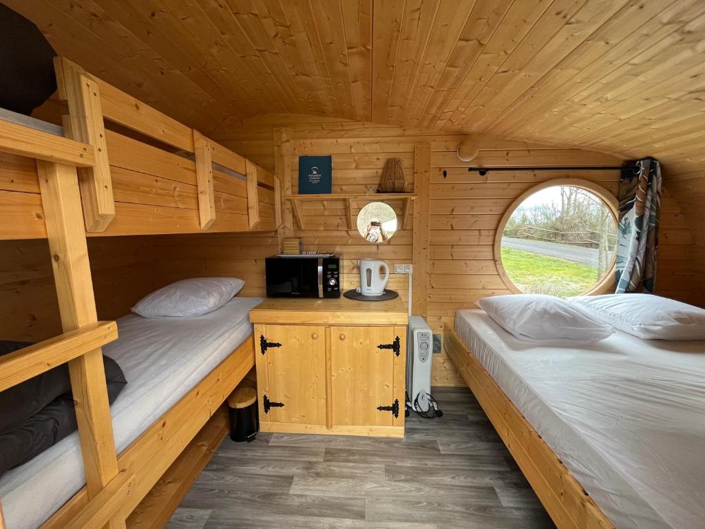 2 lits superposés dans une cabane en bois avec une fenêtre dans l'établissement Camping de la Bageasse, à Brioude