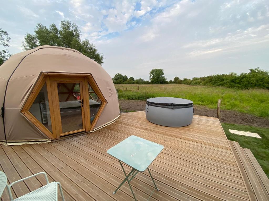 une tente sur une terrasse avec une chaise et une table dans l'établissement Dôme géodésique - Baie de Somme, à Favières