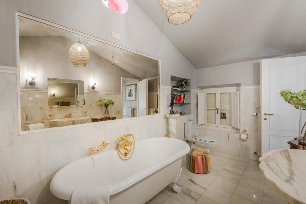 une salle de bain blanche avec une baignoire et un lavabo dans l'établissement La Chiesetta a charming Church converted into Farmhouse with Pool, à Lucques