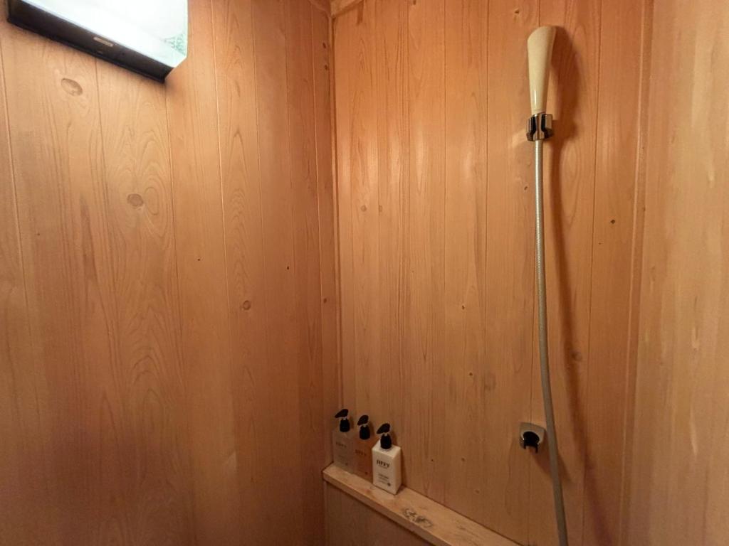 La salle de bains est pourvue d'une douche et d'un mur en bois. dans l'établissement Kira No Sato, à Itō
