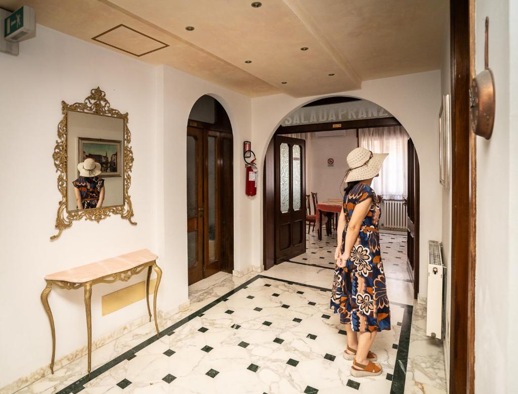 une femme portant un chapeau debout dans un couloir dans l'établissement Easy Hotel Meryon, à Sottomarina