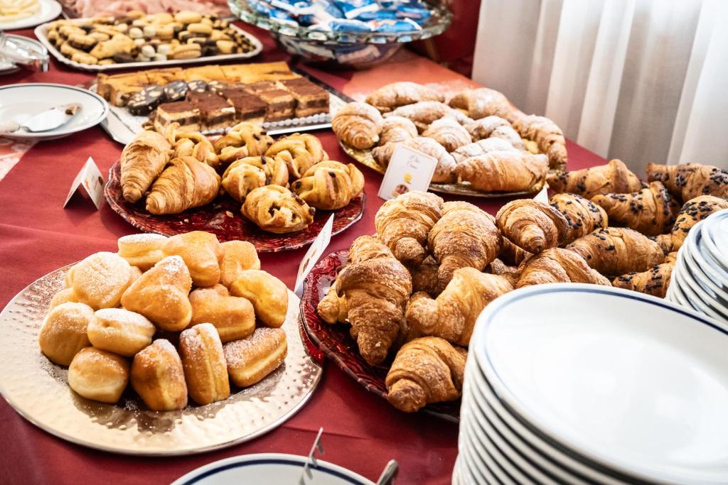 une table remplie de différents types de pâtisseries sur des assiettes dans l'établissement Easy Hotel Meryon, à Sottomarina