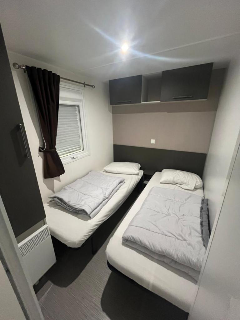 une petite chambre avec deux lits et une fenêtre dans l'établissement Mobil home spacieux 6-8 pers, camping 4 étoiles, la Carabasse, à Vias