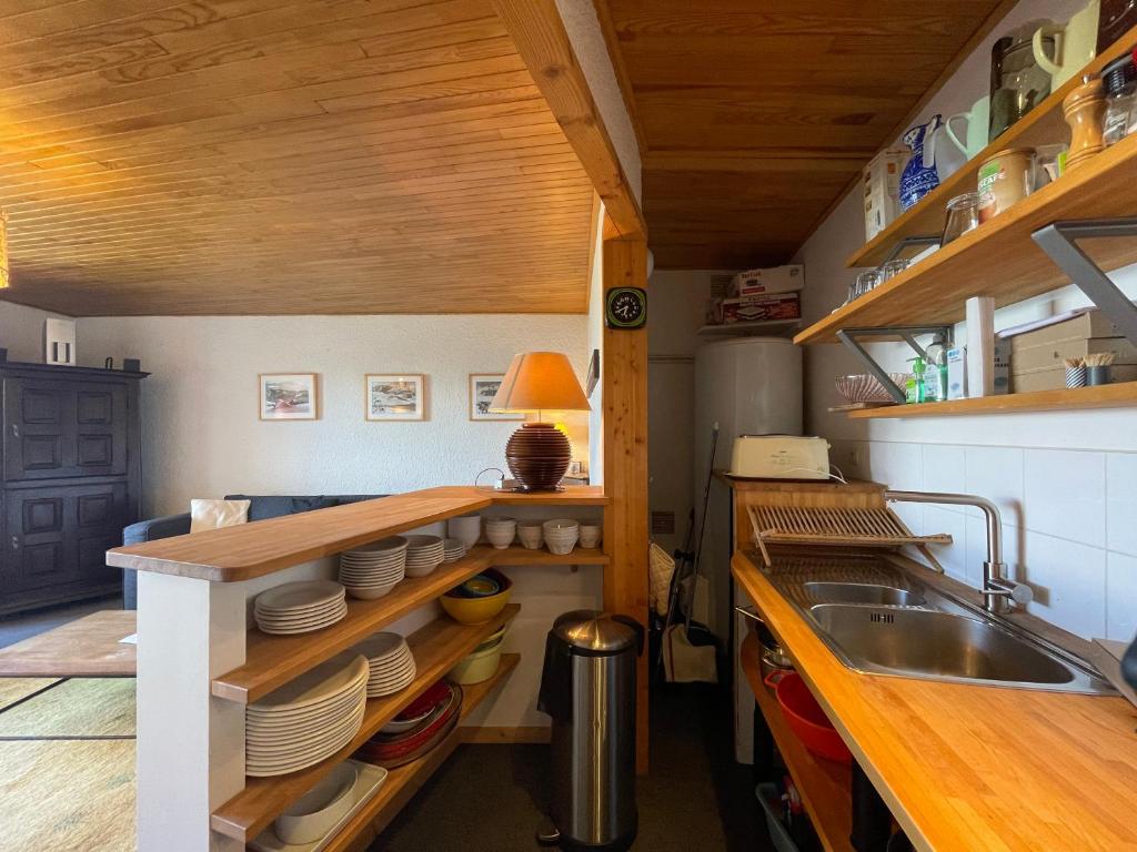 - une cuisine avec un évier et un comptoir avec des assiettes dans l'établissement Homency - Résidence de l'Oisans C5, à L'Alpe-d'Huez