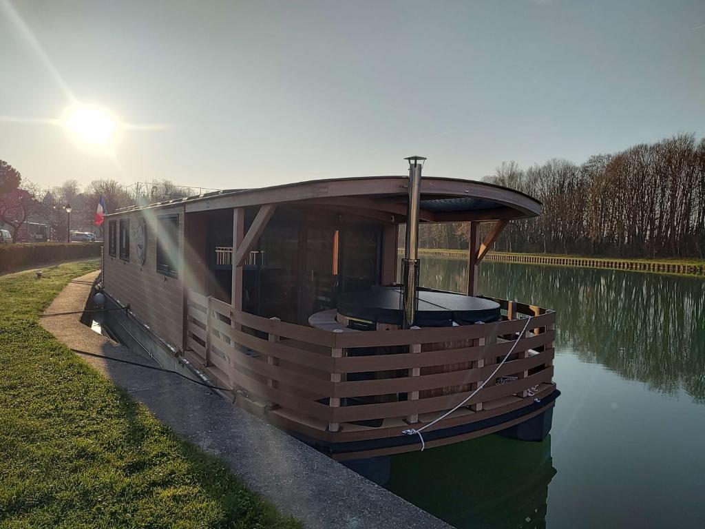 un petit bateau assis sur le bord d'une rivière dans l'établissement House Boat avec SPA naviguant en Champagne, à Mareuil-sur-Ay