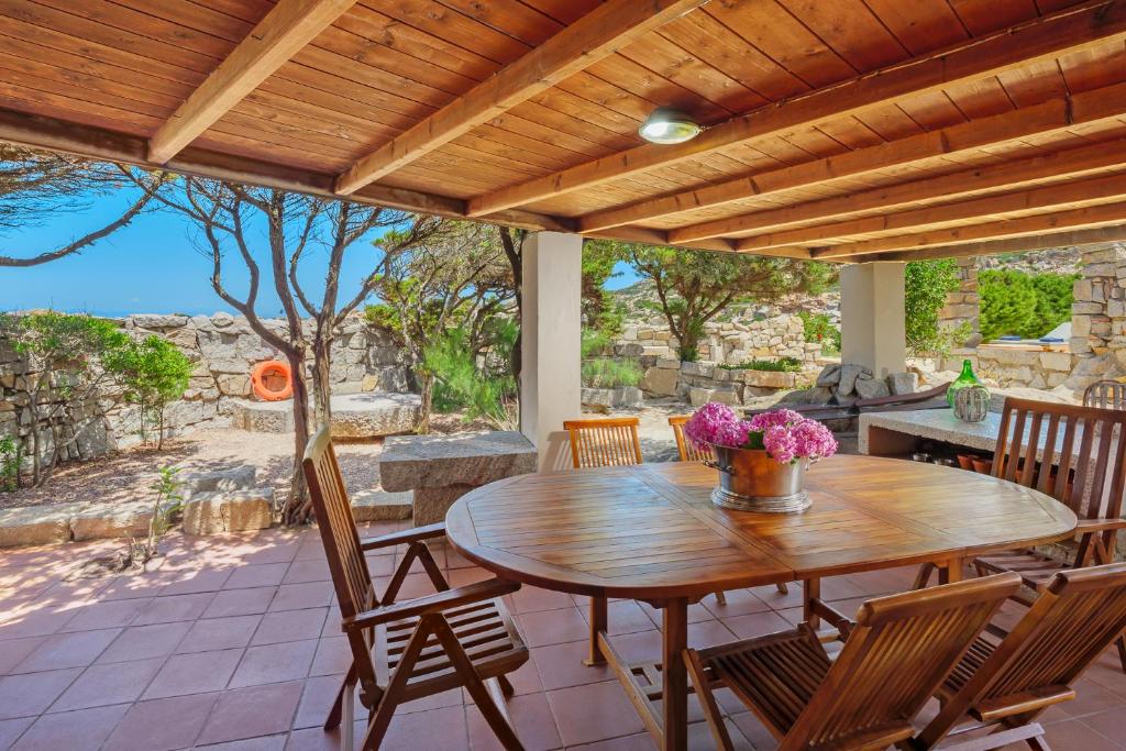 une table et des chaises en bois sur une terrasse dans l'établissement Villa Itaca - Swimming pool by the Sea, à La Maddalena