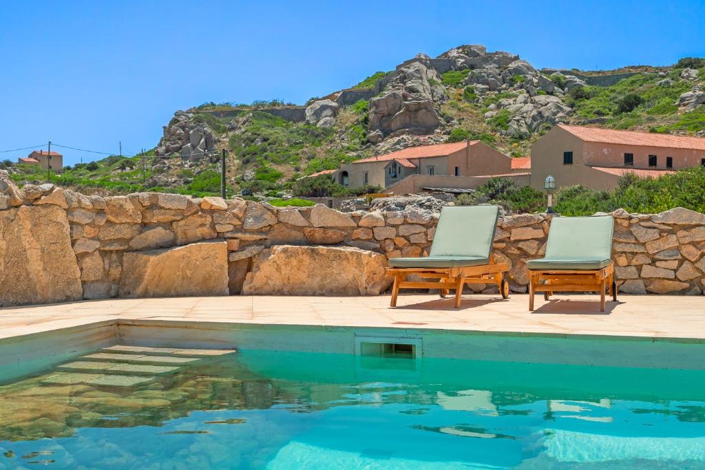 deux chaises assises à côté d'une piscine dans l'établissement Villa Itaca - Swimming pool by the Sea, à La Maddalena