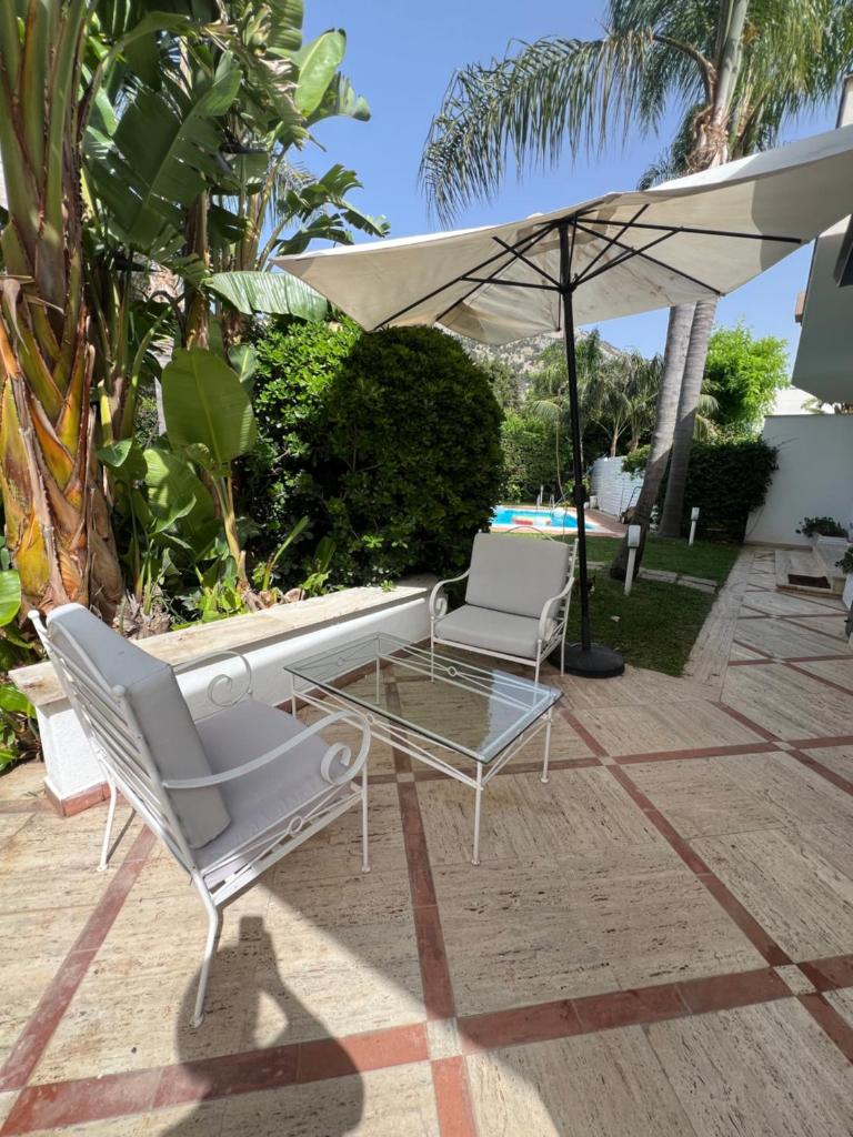 un patio avec une table, des chaises et un parasol dans l'établissement Villa Losanna, à Mondello