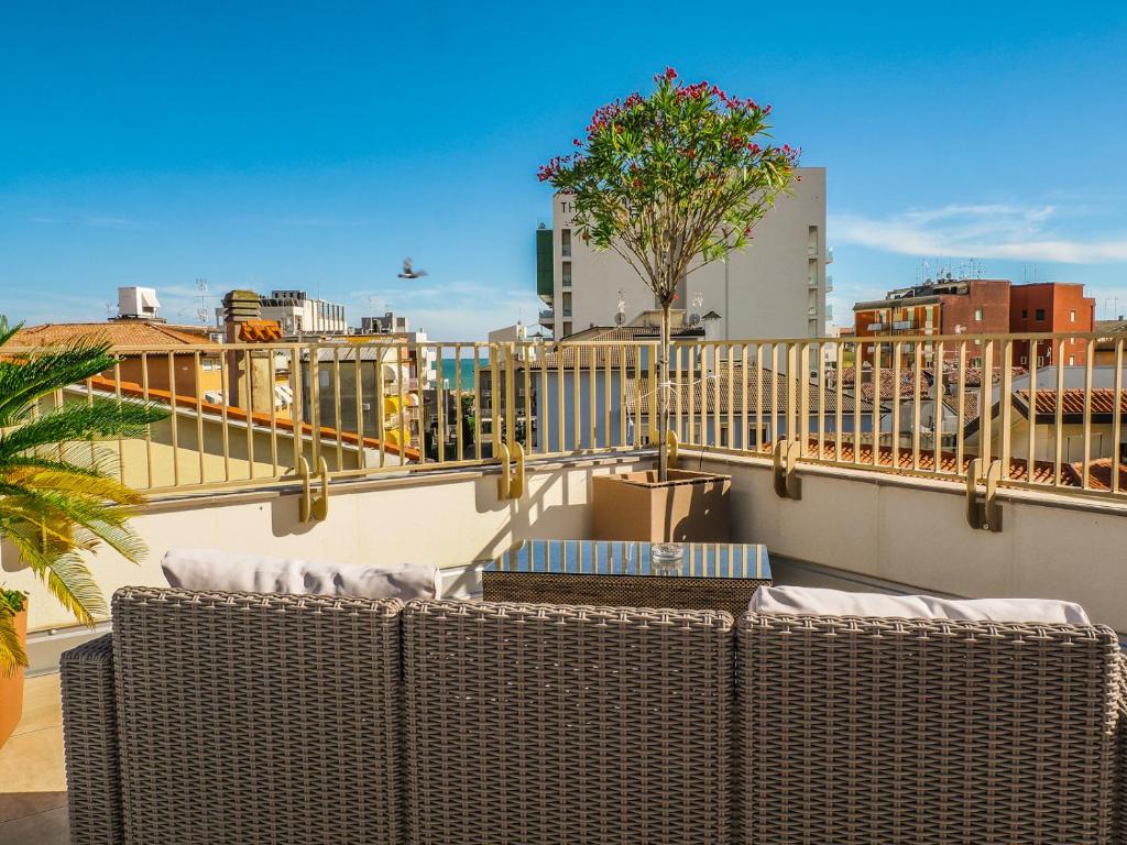 d'un balcon avec des chaises en osier et une vue sur la ville. dans l'établissement Hotel Angelo, à Caorle