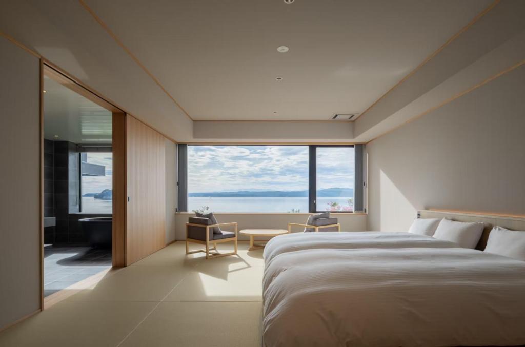 une chambre avec un grand lit et une grande fenêtre dans l'établissement 一 能登島 hitotsu notojima, à Kōda