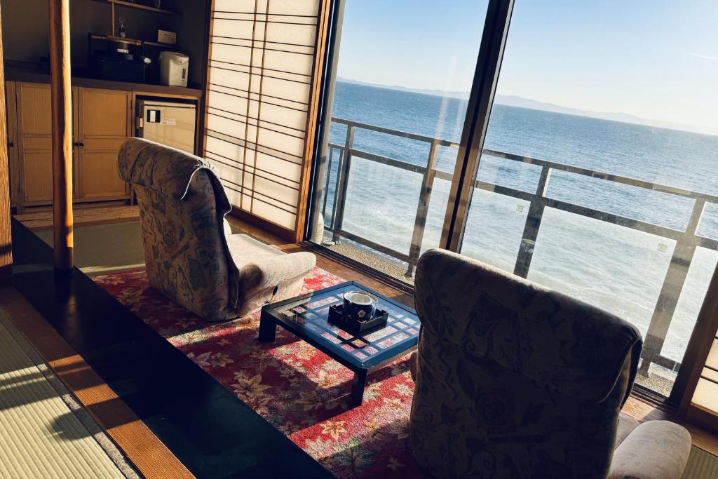 - un salon avec deux chaises et une table devant une fenêtre dans l'établissement Shuku Kaifuu, à Minamichita