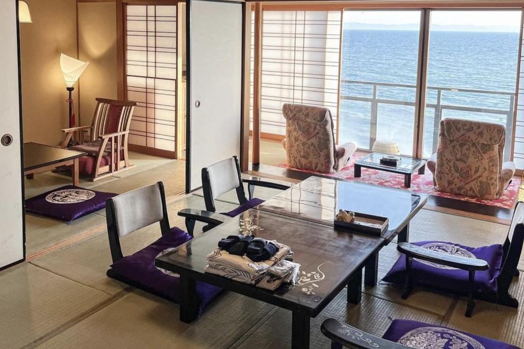 une salle à manger avec une table et des chaises et l'océan dans l'établissement Shuku Kaifuu, à Minamichita