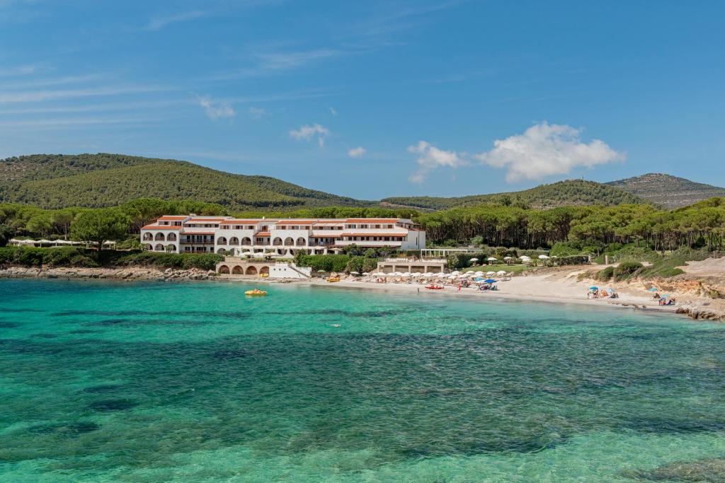 un complexe sur une plage avec des gens dans l'eau dans l'établissement Hotel Punta Negra, à Alghero