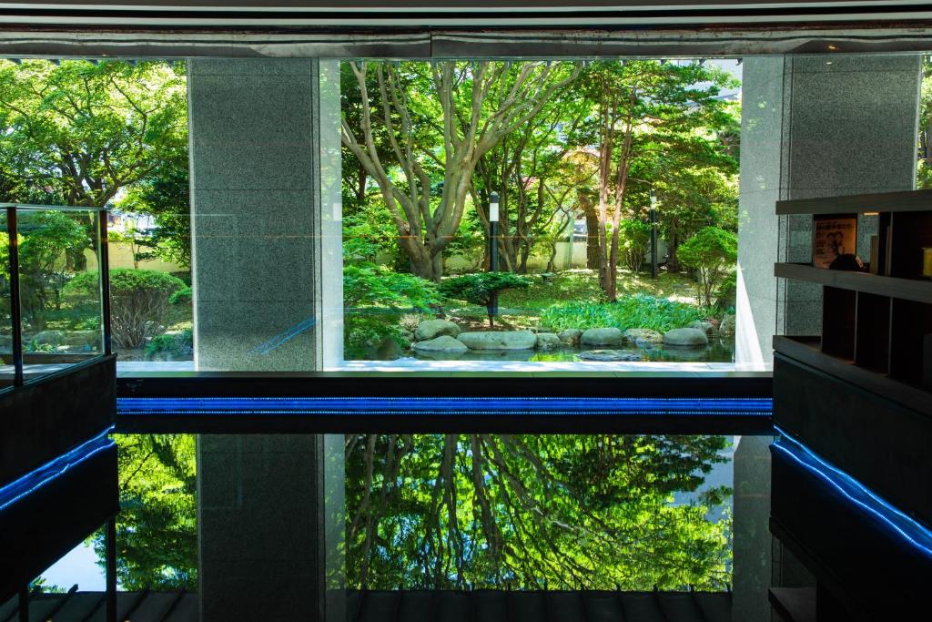 un reflet d'un jardin dans une piscine dans une maison dans l'établissement Bourou Noguchi Hakodate, à Hakodate
