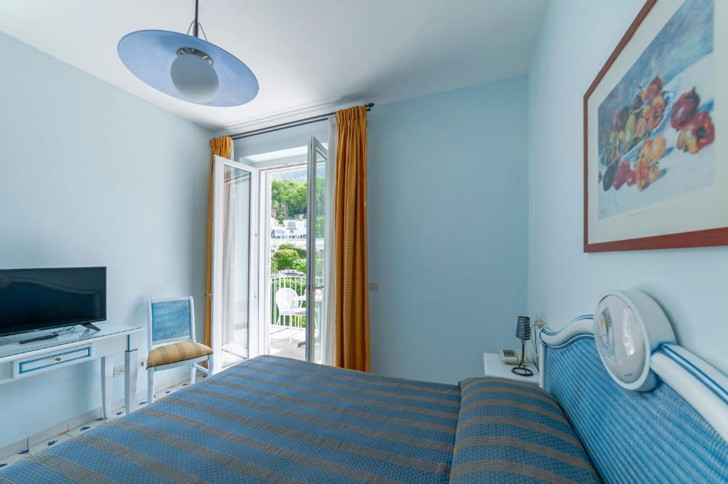 - une chambre bleue avec un lit et une télévision dans l'établissement Hotel Gran Paradiso, à Ischia