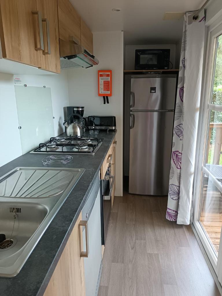 La cuisine est équipée d'une cuisinière, d'un évier et d'un réfrigérateur. dans l'établissement Standing PREMI-HOME moderne et spacieux 25min Puy DuFou 700RC, à La Boissière-de-Montaigu