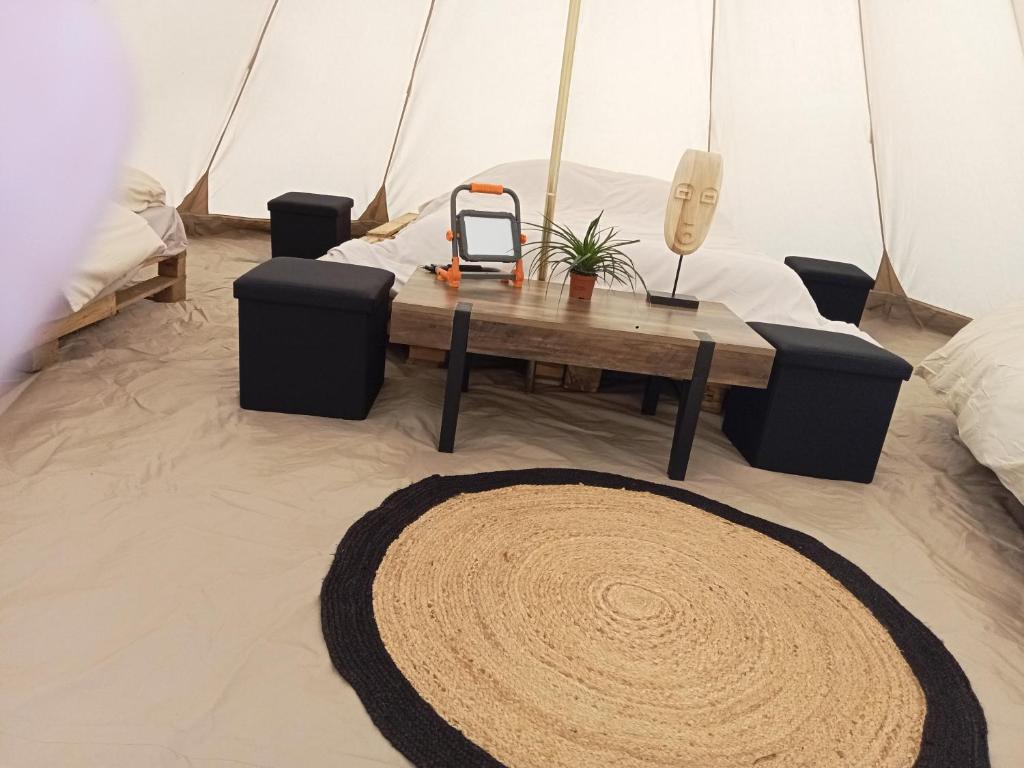 Cette chambre comprend une tente avec une table et un tapis. dans l'établissement tipi insolite 1 a 4 personnes, à Plouray
