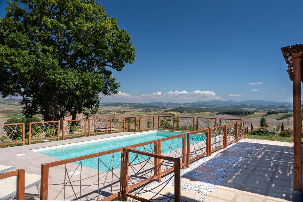 une piscine avec une balustrade en bois à côté d'un arbre dans l'établissement Villa San Giuseppe Scirocco, à Montecatini Val di Cecina