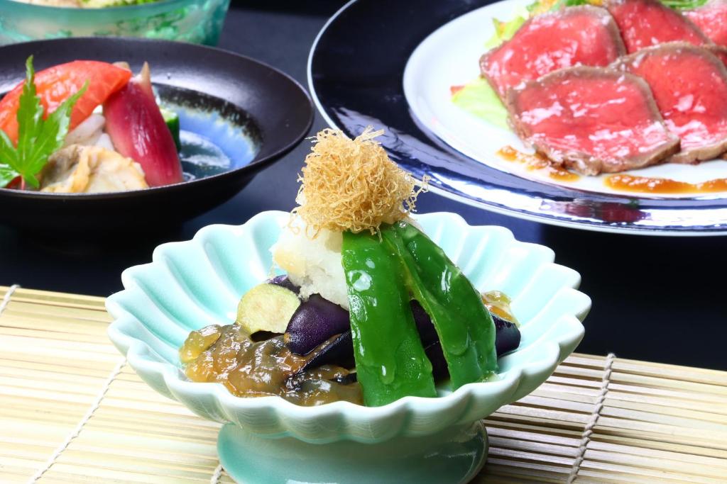 un bol de nourriture sur une table avec des assiettes de nourriture dans l'établissement Baigetsu Ryokan, à Shimo-suwa