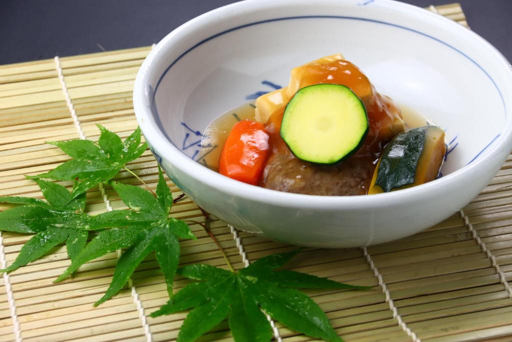 un bol de nourriture avec des légumes et un concombre dans l'établissement Baigetsu Ryokan, à Shimo-suwa