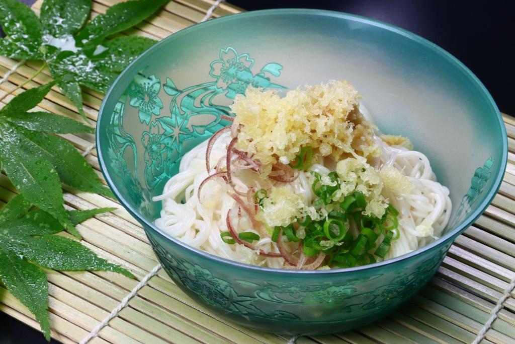 - un bol rempli de nouilles et de légumes sur une table dans l'établissement Baigetsu Ryokan, à Shimo-suwa