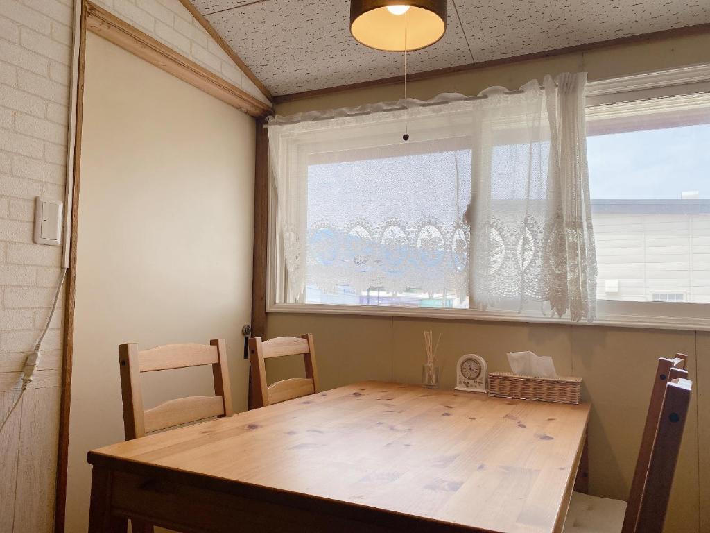 une salle à manger avec une table en bois et une fenêtre dans l'établissement Ryokan Sansui, à Furano