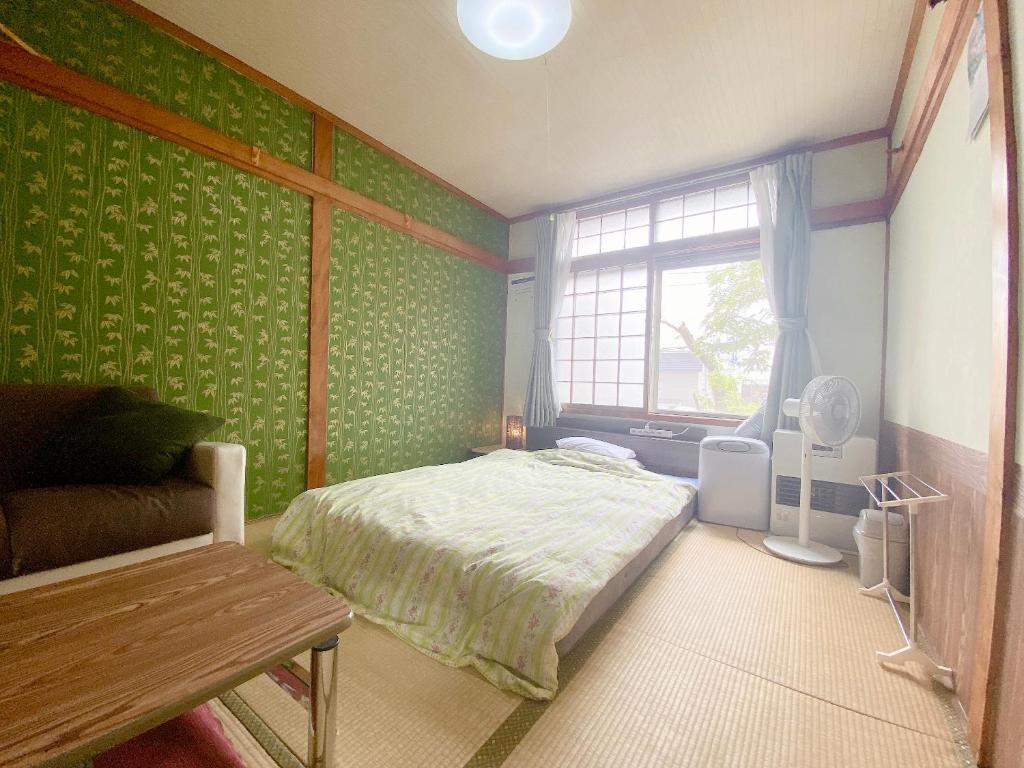 - une chambre avec des murs verts, un lit et une fenêtre dans l'établissement Ryokan Sansui, à Furano