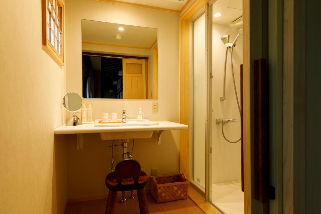 une salle de bain avec un lavabo et une douche avec un miroir dans l'établissement Motoyu Ishiya, à Kanazawa