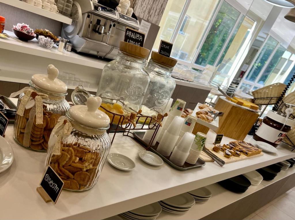 un comptoir avec plusieurs pots de biscuits et autres pâtisseries dans l'établissement Hotel Vernel, à Rimini