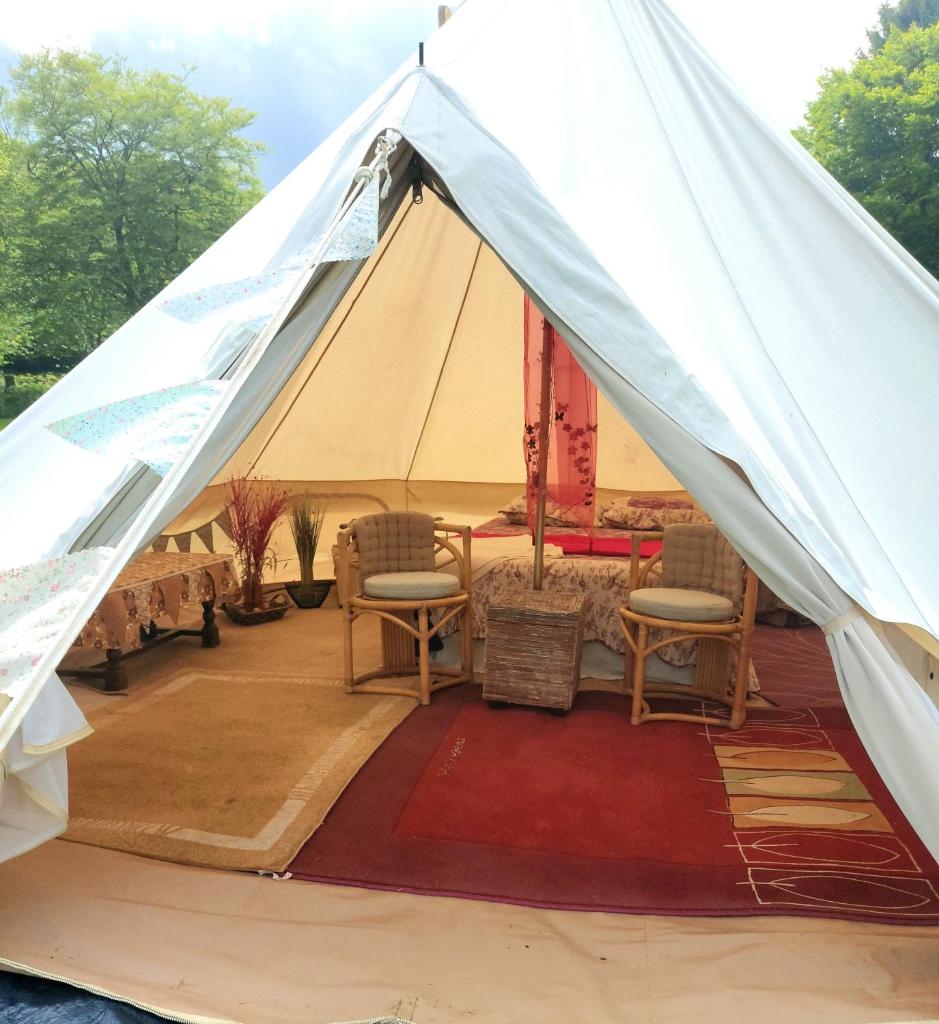 une tente avec des chaises et une table. dans l'établissement Bell tent one of three to rent fully equipped private equipped kitchen tents too, à Saint-Michel-de-Montjoie