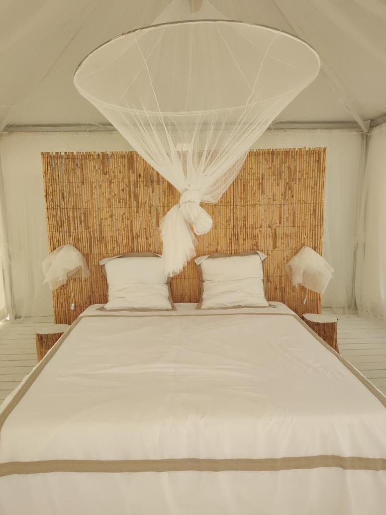 un grand lit blanc avec des draps et des oreillers blancs dans l'établissement Glamping at Séraphin's, à Navacelles
