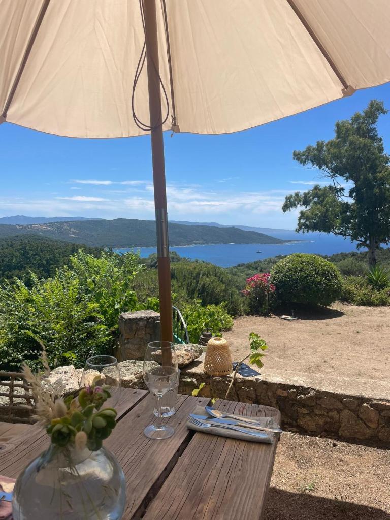 - une table avec un parasol et une vue sur l'eau dans l'établissement A Malgrana - Tente lodge hébergement insolite, à Coti-Chiavari