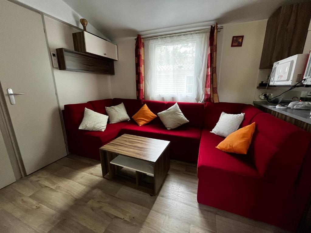 un salon avec un canapé rouge et une table dans l'établissement Superbe Mobilehome 3 ch, climatisé tout confort, à Onesse-et-Laharie