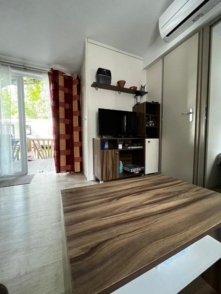 un salon avec une table et une télévision dans l'établissement Superbe Mobilehome 3 ch, climatisé tout confort, à Onesse-et-Laharie