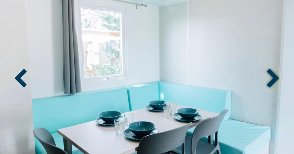 une salle à manger avec une table et des chaises et une fenêtre dans l'établissement Mobilhome dans camping 4 étoiles, au Cap d'Agde