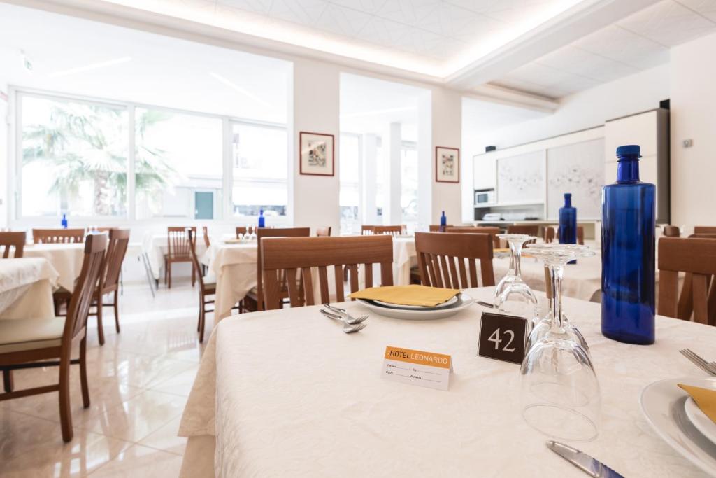 une salle à manger avec des tables blanches et des vases bleus dans l'établissement Hotel leonardo, à Cattolica