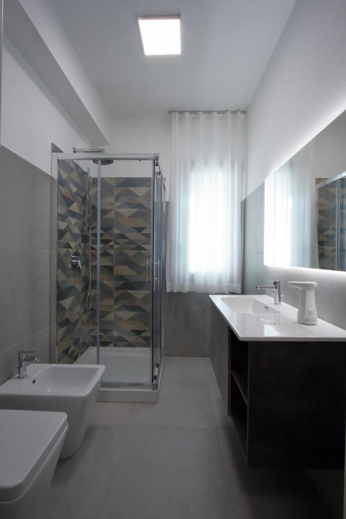 une salle de bain blanche avec deux lavabos et une douche dans l'établissement villa grecale, à Castellammare del Golfo