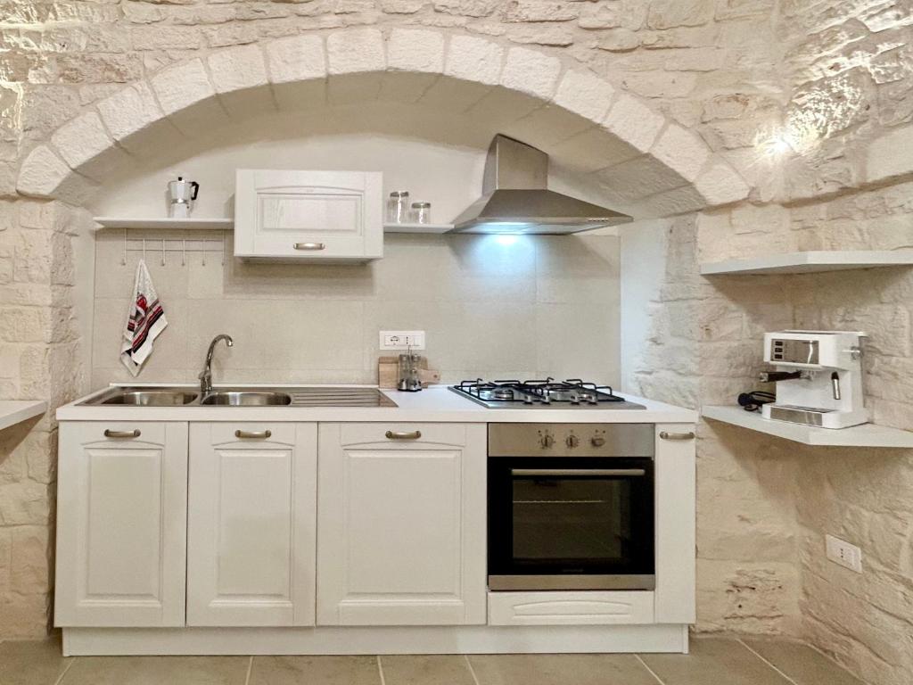 Il comprend une cuisine avec une cuisinière et un mur en pierre. dans l'établissement Lamia Itria, à Martina Franca