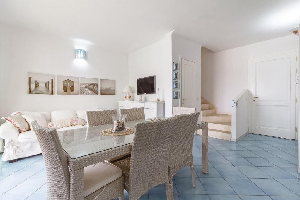 une salle à manger avec une table, des chaises et un canapé dans l'établissement Villetta Marina Vista mare con piscina privata, à Stintino