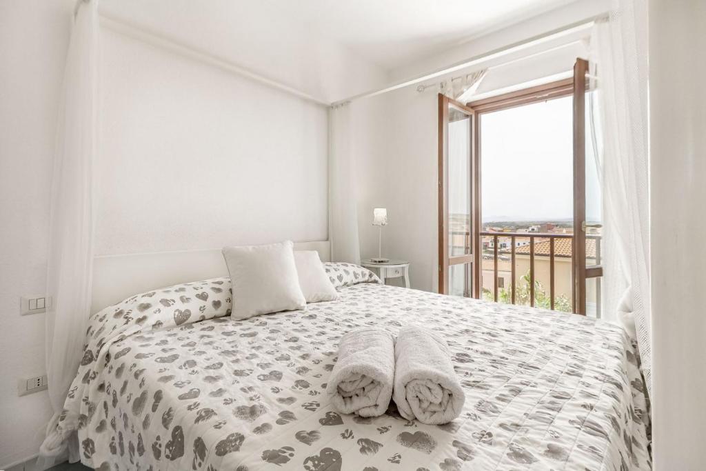 une chambre blanche avec un lit avec des serviettes dessus dans l'établissement Villetta Marina Vista mare con piscina privata, à Stintino