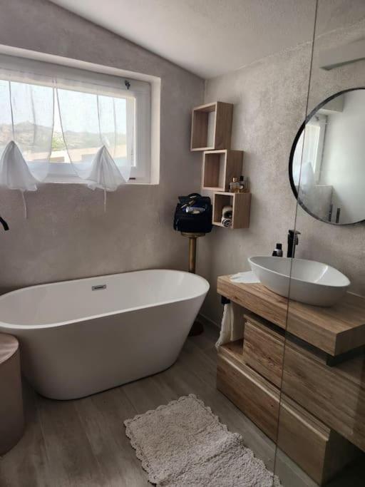 La salle de bains est pourvue d'une grande baignoire blanche et d'un lavabo. dans l'établissement Villa Rosi, à Costa Paradiso