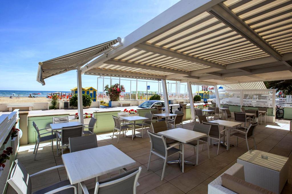 une terrasse avec des tables et des chaises et la plage dans l'établissement San Marco, à Marotta