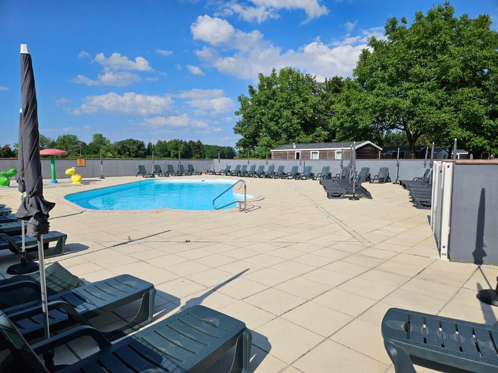 une piscine avec des chaises et un parasol dans l'établissement Mobil-home climatisé (proximité EUROPA PARC), à Boofzheim