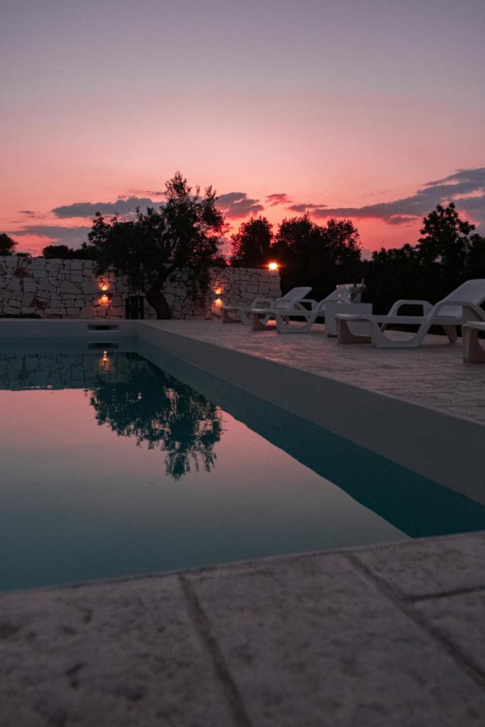 une piscine avec des chaises et un coucher de soleil en arrière-plan dans l'établissement Villa Geco, à Specchiolla