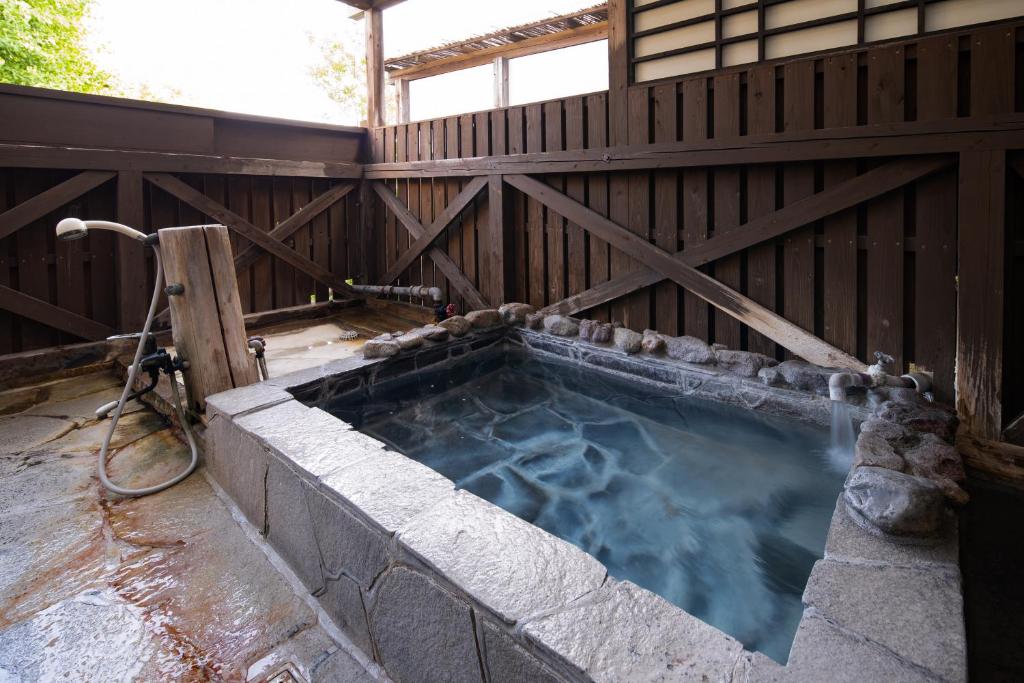 un jacuzzi dans un bâtiment avec une clôture dans l'établissement Hozanso Beppu, à Beppu