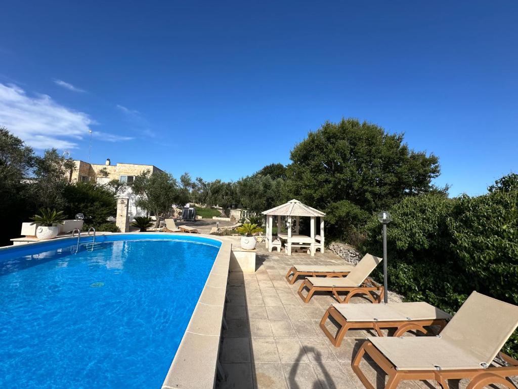 une piscine avec des chaises et un gazebo dans l'établissement Il Giardino di Maria - Villa Exclusive Use, à Ostuni