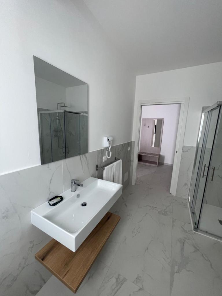 une salle de bain blanche avec un lavabo et un miroir dans l'établissement Hotel Diadema, à Diamante